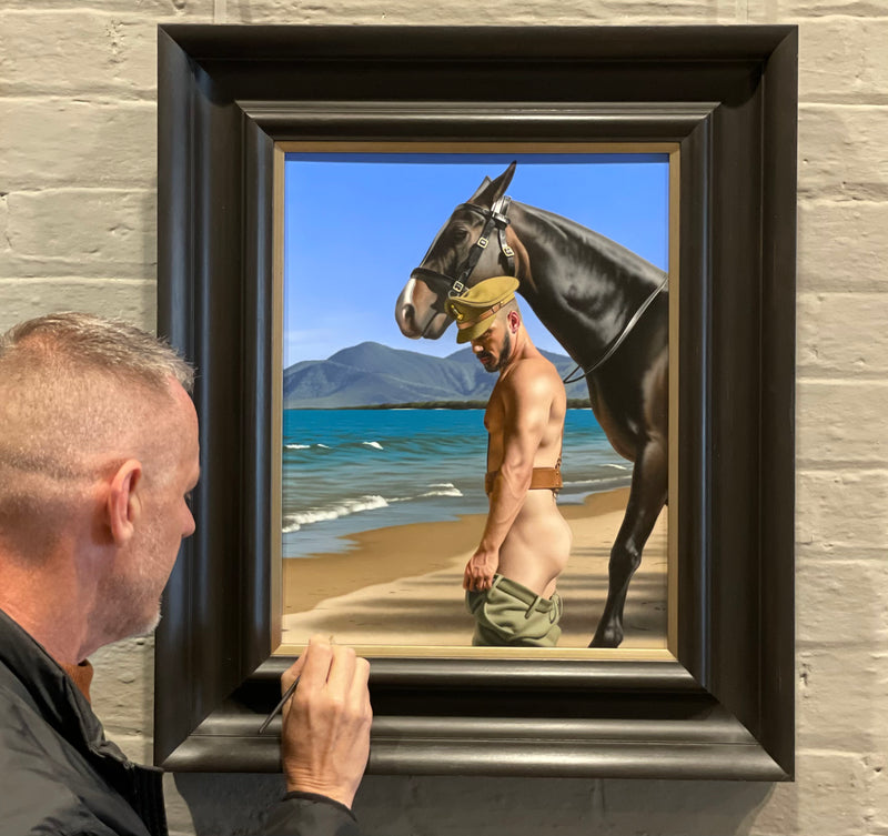 Ross Watson signing an original oil painting in a heavy black italianate frame of a partially dressed soldier with a horse on a beach
