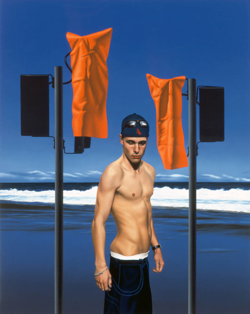 Portrait of young man with his pants pulled low wearing a baseball cap backward on the beach with two speaker stands either side contain two speakers with one on each stand covered in orange covers